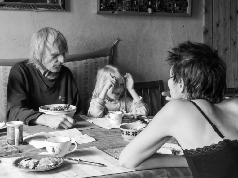Drei Menschen an einem Küchentisch essen zusammen Brote.