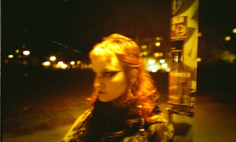 Porträt einer Person im gelblichen Licht mit auffälligem Augen-Make-up.