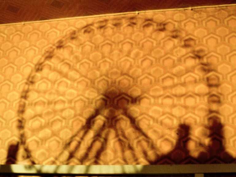 Schatten eines Riesenrads auf einer Wand mit sechseckigem Muster