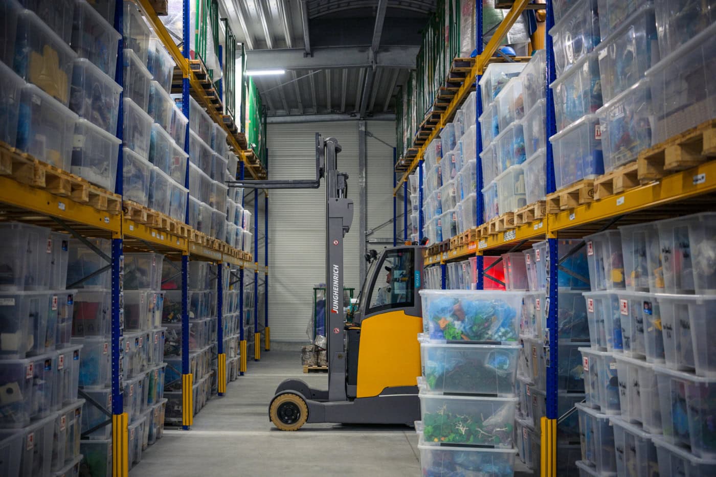 Playmobil Diorama Künstler Oliver Schaffer fährt mit dem Stapler durch sein Hochregallager. Er holt eine Palette aus dem Regal.