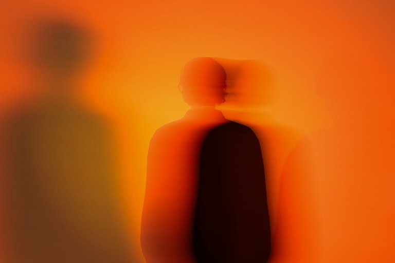 unscharfe Silhouette vom Oberkörper vor orangenem Hintergrund