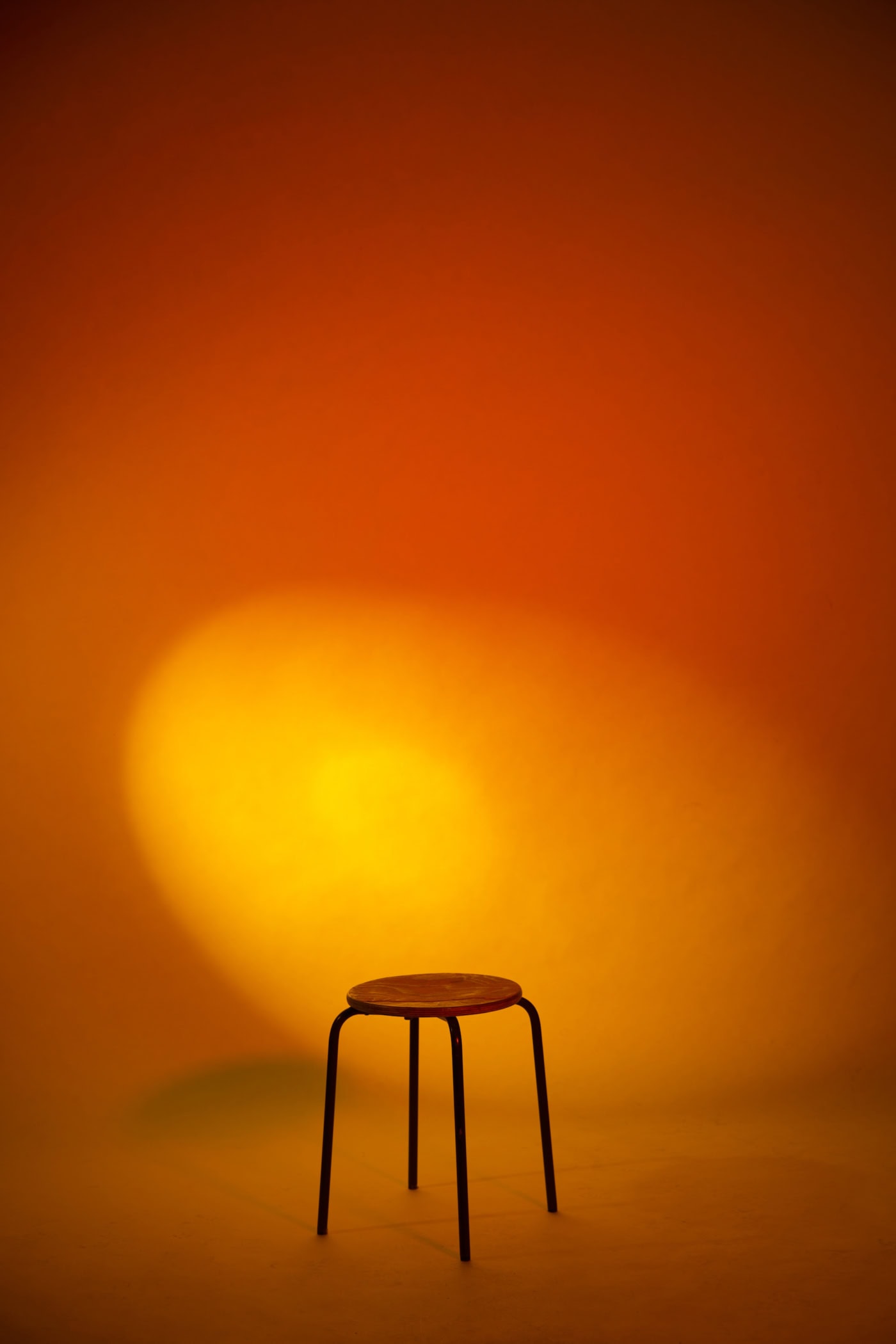 Hocker vor orangenem Hintergrund mit Lichtakzent