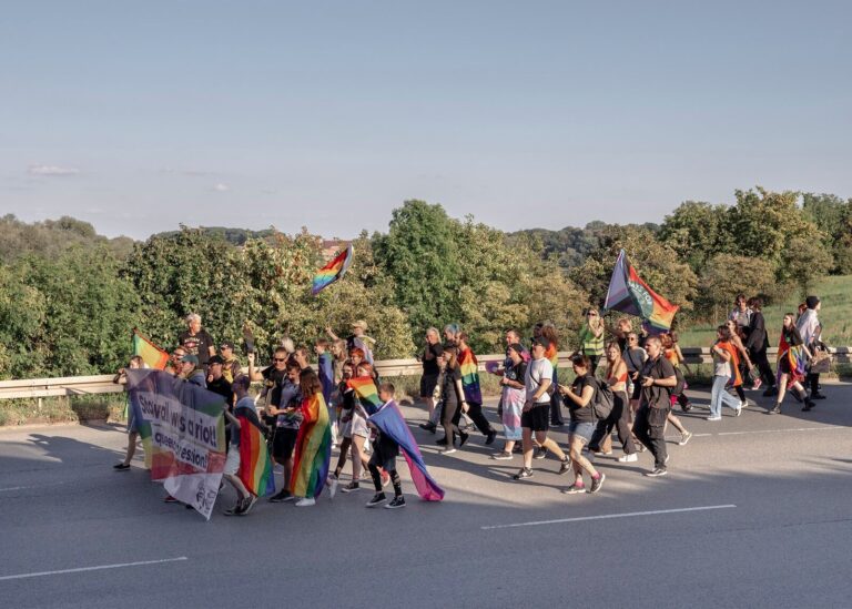 Demonstrationszug mit Regenbogenfahnen auf einer Landstrasse