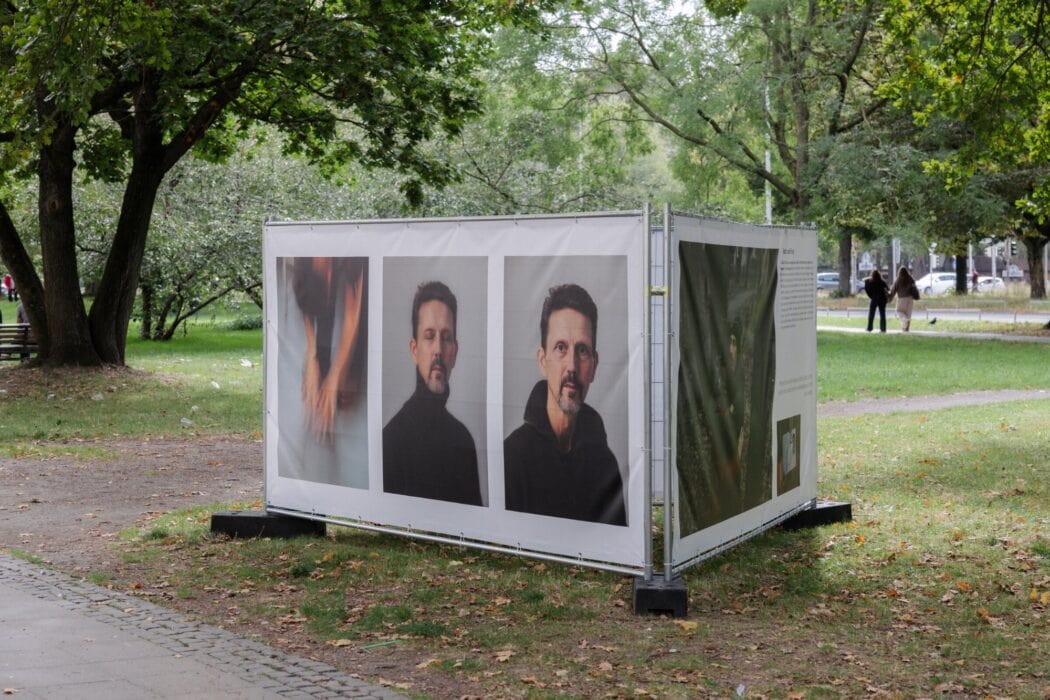 Weisse Ausstellungskabine mit Portraets unter Baeumen am Leibnizufer Hannover