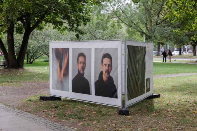 Weisse Ausstellungskabine mit Portraets unter Baeumen am Leibnizufer Hannover