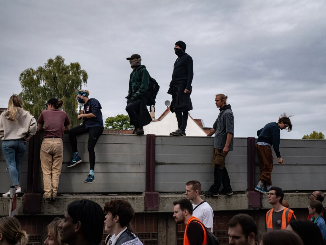 Demonstrierende stehen auf einer Lärmschutzwand.