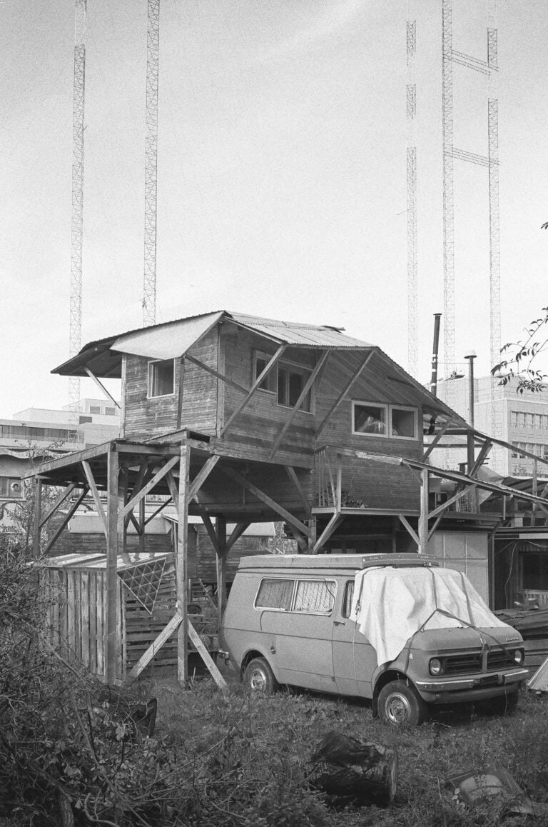 Ein mit einem Tuch abgedeckter Van steht unter einer aus Holz gebauten Hütte.