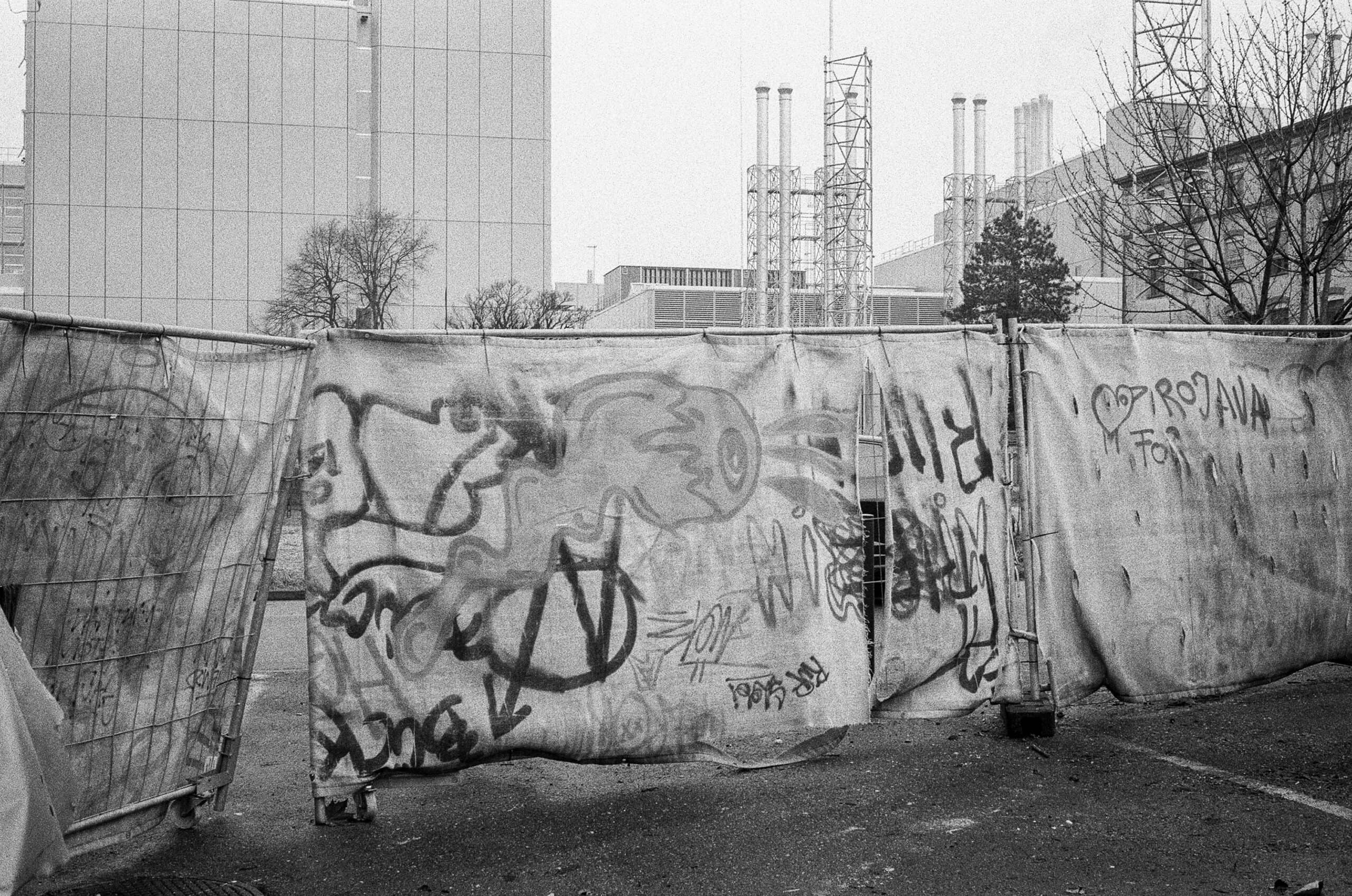 Mit Graffiti besprühte Bauzäune trennen das Areal gegen hinten ab.