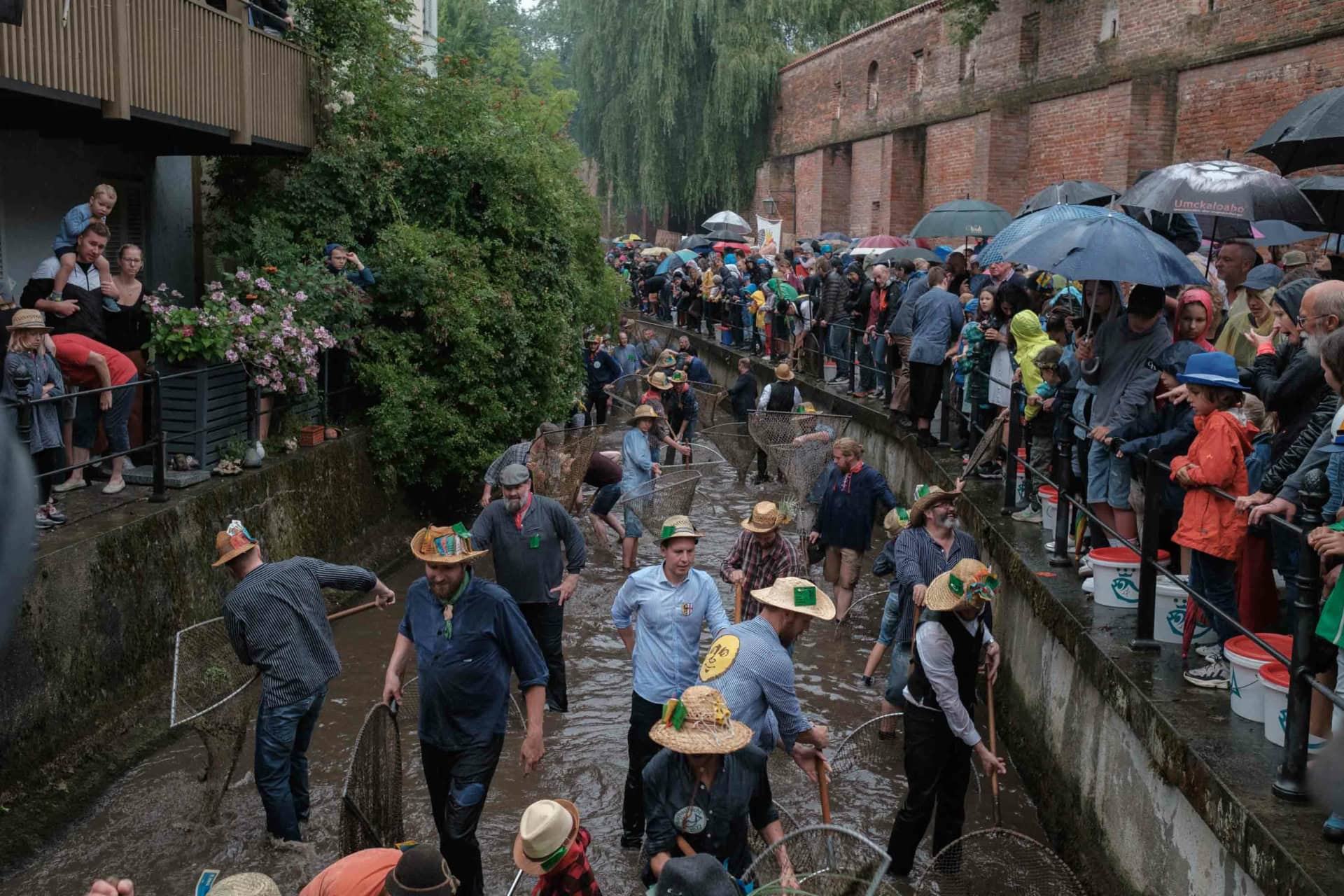 Stadtbach Memmingen, Am Einlass unweit des Bettelturms, über eine Strecke von ca. 1 km springen die Fischer*innen ins Wasser und werden von den Zuschauer*innen angefeuert. Es ist hektisch und rau.