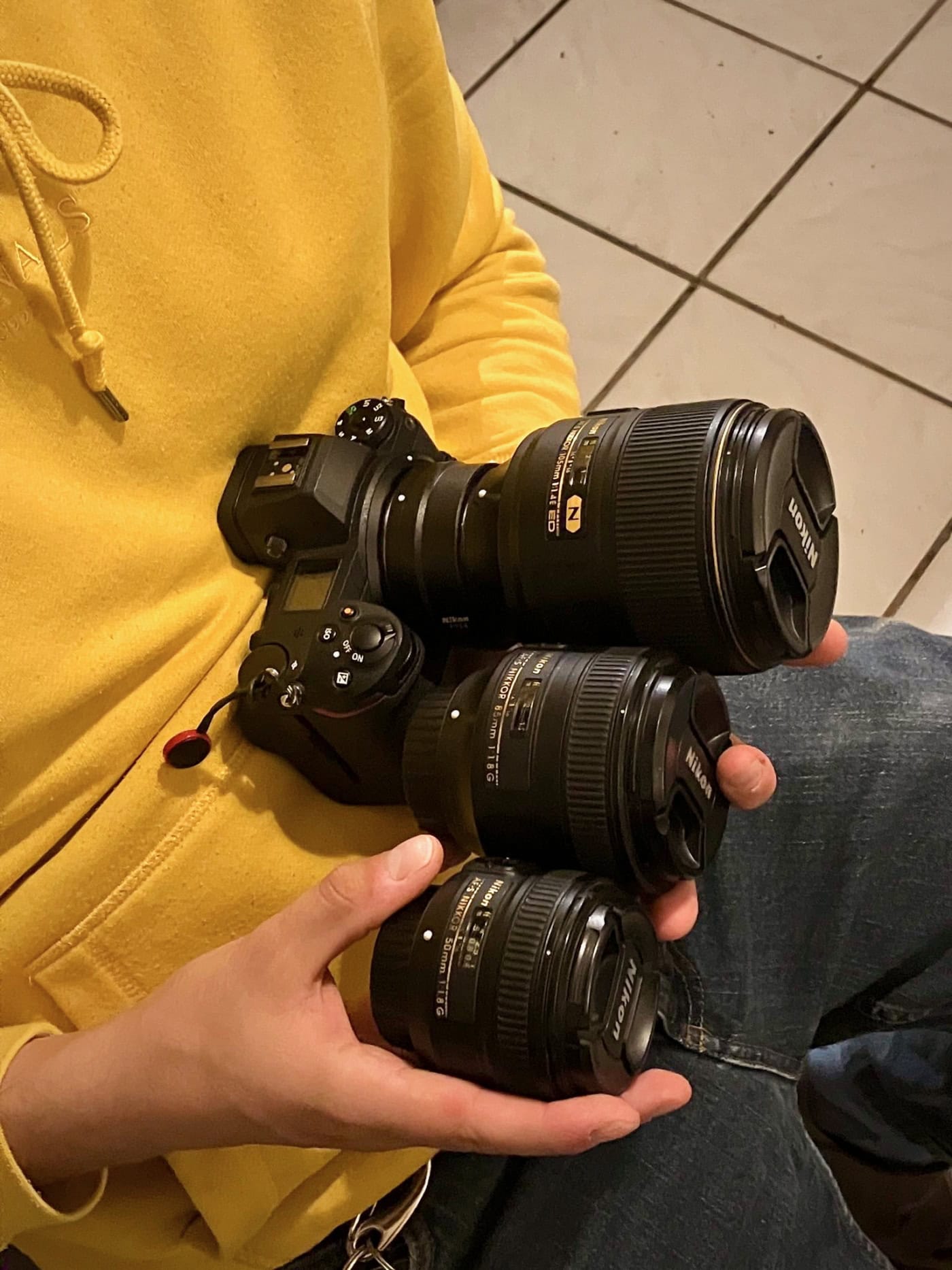 Ein Mann hölt eine Kamera und mehrere Objektive in den Händen.