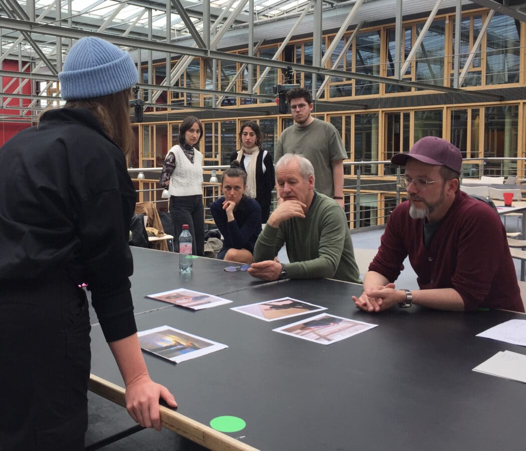 A student from Hanover University of Applied Sciences and Arts presents her photo series to GEO editors. Recorded at the Design Center of the Hanover University of Applied Sciences and Arts. Other students observe the scene in the background.