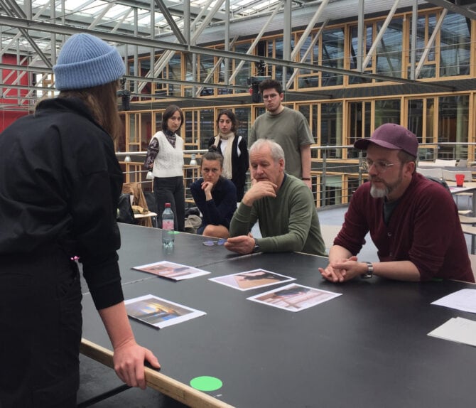 Eine Studentin der Hochschule Hannover stellt GEO-Redakteuren ihre Fotostrecke vor. Aufgenommen im Design Center der Hochschule Hannover. Weitere Studierende beobachten die Szene im Hintergrund.