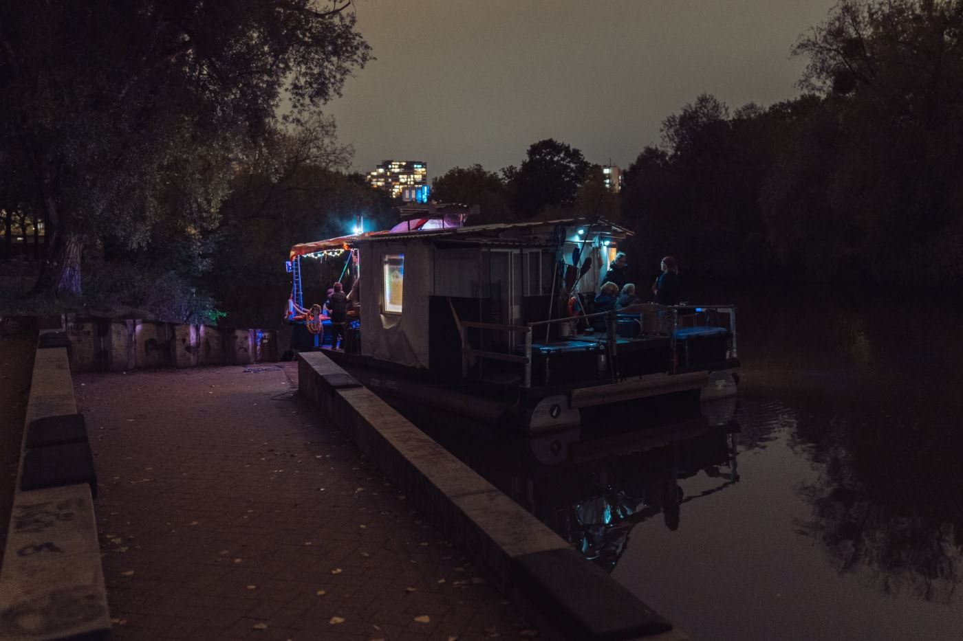 Ein Schiffanleger in der Dunkelheit, einzig allein erleuchtet durch das Licht aus dem Hausboot, das an dem Anleger hält.