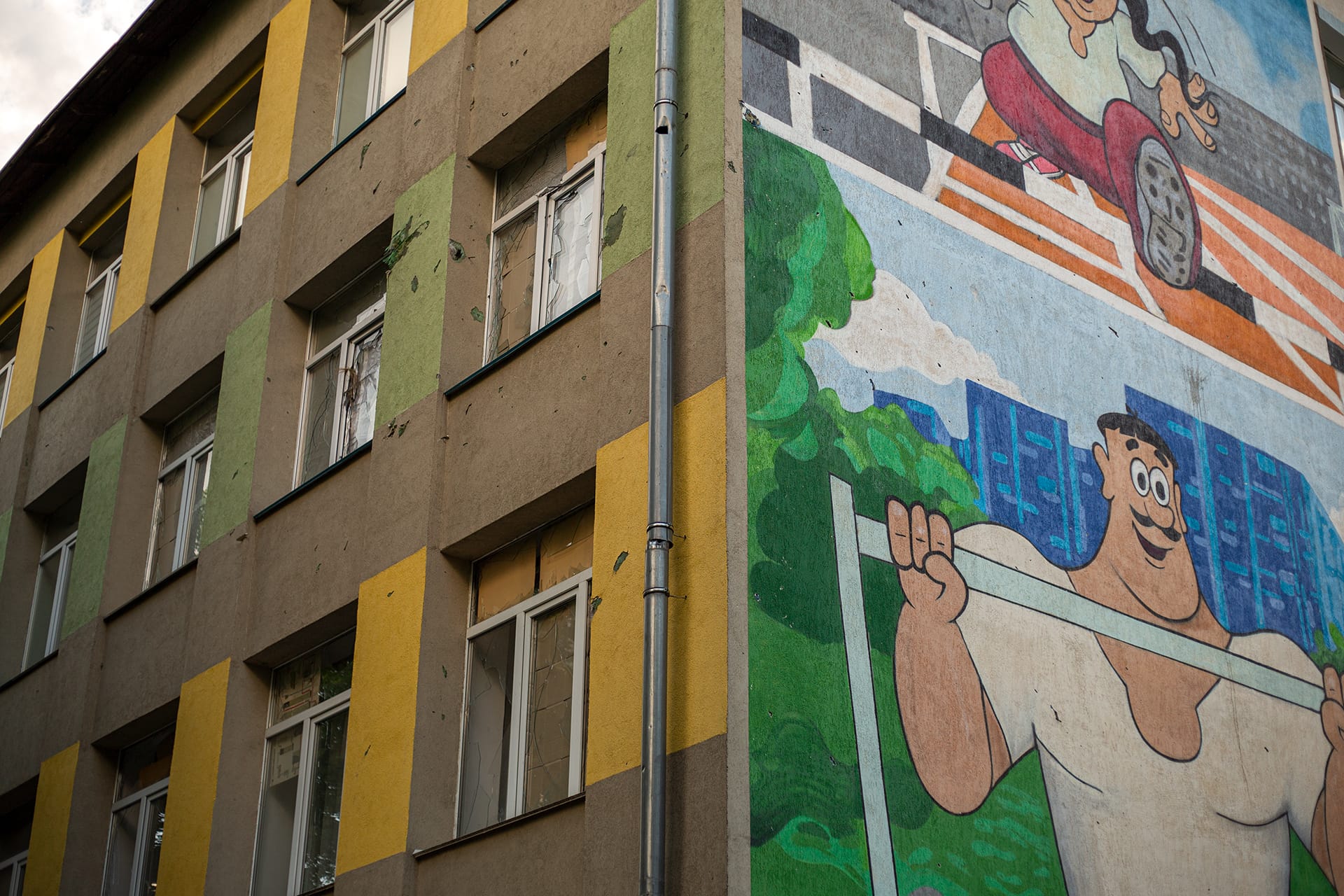 Zerbrochene Fensterscheiben und ein Graffito auf einer Häuserwand in Kiev im Mai 2023, fotografiert von Tetyana Chernyavska