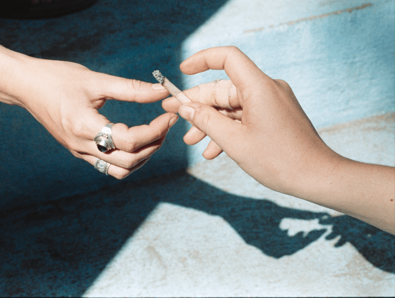 Zwei Hände teilen sich in antik anmutender Ästhetik eine Zigarette, Blitz, Editorial, Fotografie, Rauchen, Sucht