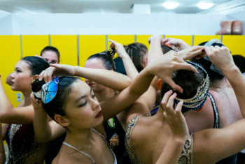 Junge Synchronschwimmerinnen der SGS Hannover stehen nach ihrem Showschwimmen-Auftritt in einer Umkleidekabine und öffnen sich gegenseitig die Haare.