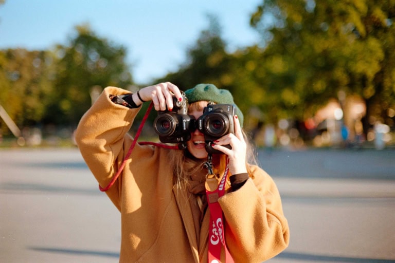 Eine Frau hält sich zwei Kameras vor die Augen.