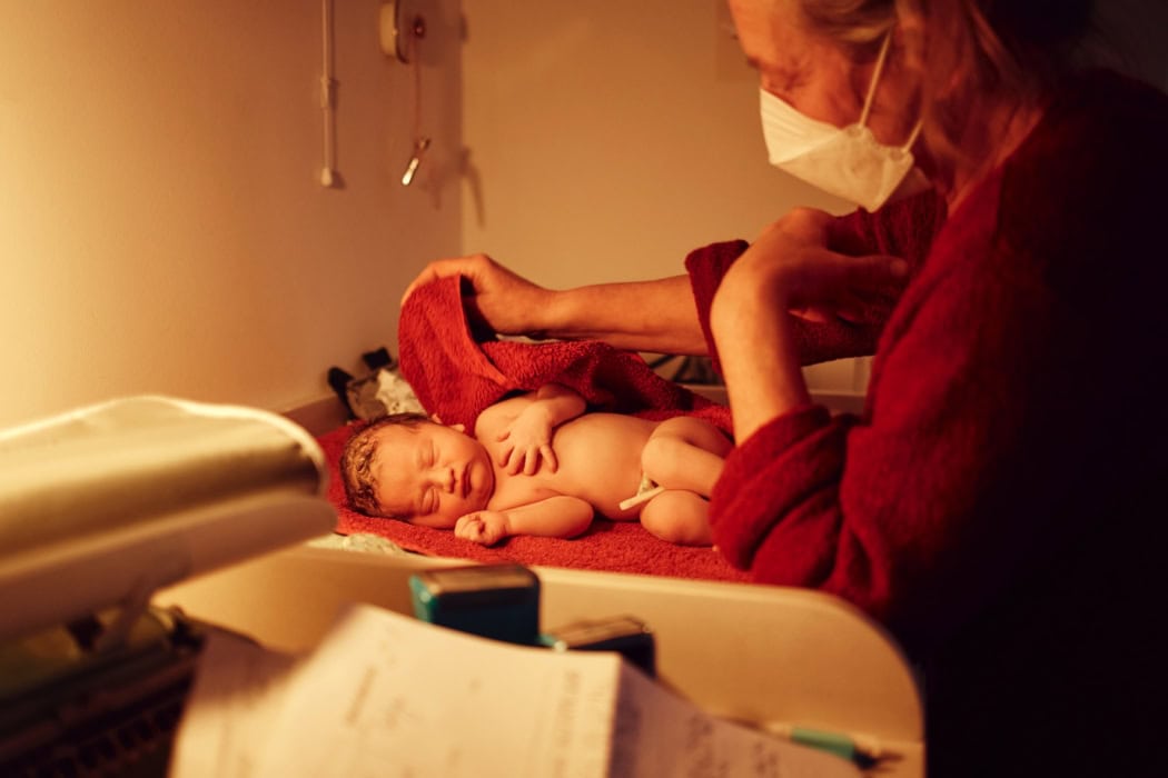 Eine Hebamme kümmert sich um ein Neugeborenes.