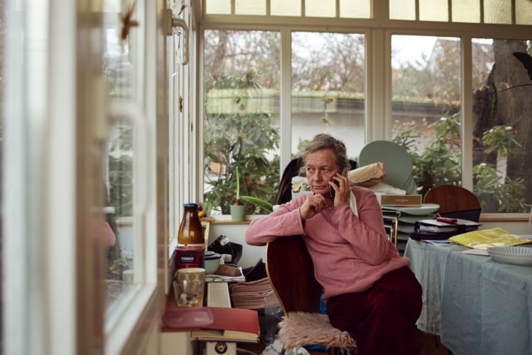 Eine Frau telefoniert in einem lichtdurchfluteten Raum. Man sieht ihr Gesicht: Sie wirkt interessiert und konzentriert.