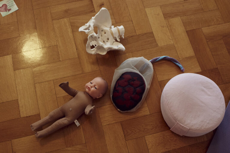 A doll, a model of a pelvis and a fabric placenta with amniotic sac and umbilical cord lie on the floor. In the antenatal class, the objects illustrate how a birth unfolds.