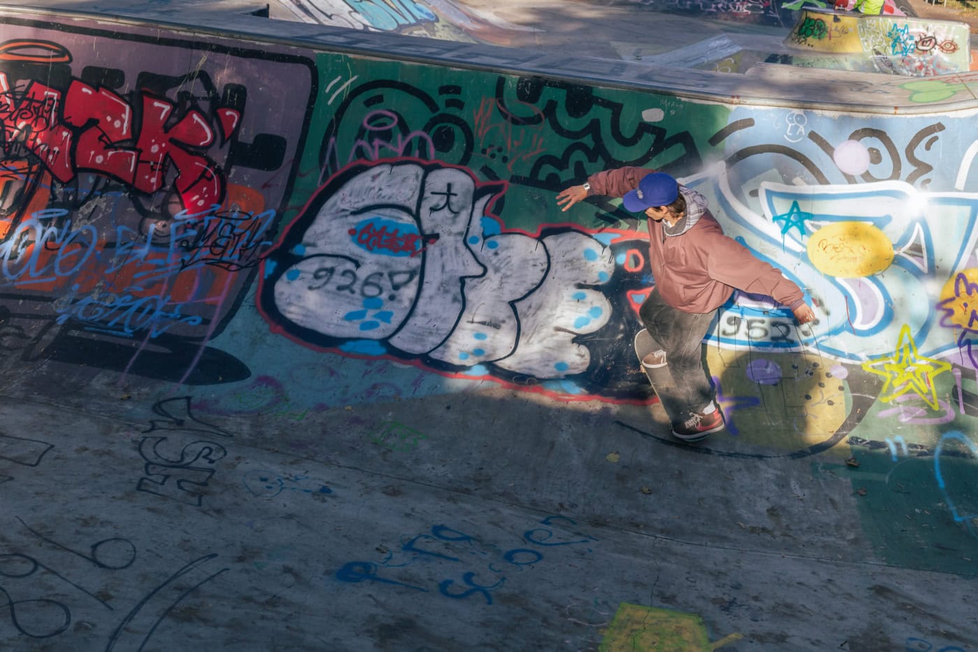 Ein junger Mann auf einem Skateboard am Abend. Licht bei Sonnenuntergang. Viele Graffiti in der Skateboarding Area.