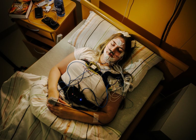 Sommer liegt in einem Bett des Schlaflabors. Sie ist verkabelt und hat die Augen verschlossen.